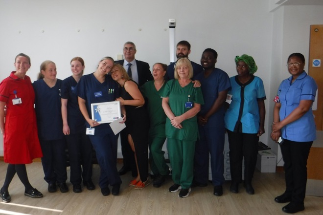 A photo of staff nurse Jade Ryan along with the rest of the ward 11 team at The Christie, receiving her You Made a Difference Award for August 2024 from Christie Chief Executive Roger Spencer.