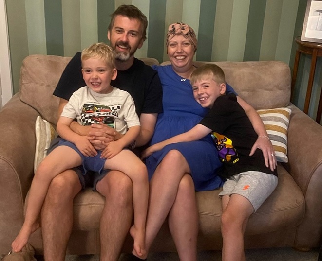 A photo of Christie patient Elaine, her husband Alastair, and her 2 sons Stanley and Alfie sitting on a couch.