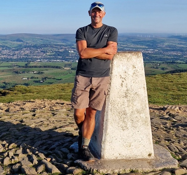 A photo of Christie patient and Christie Charity supporter Lee Penrose standing on top of a hill.