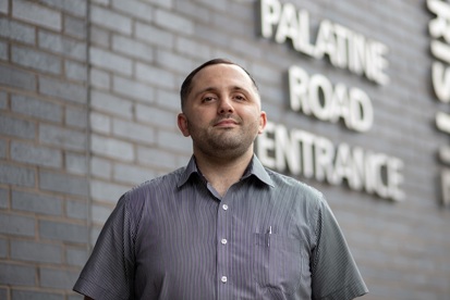 A photo of Sean McGagh, porter at The Christie standing outside the Palatine Road Entrance to the hospital.