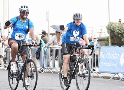 A photo of Christie supporter and staff member Rupert Ajelo taking on The Christie Charity's Manchester to Blackpool bike ride alongside another cyclist.