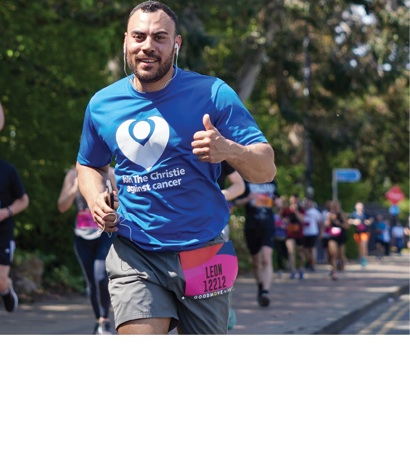 A man running in a mass participation event wearing a Christie Charity t-shirt.
