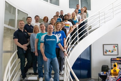 A photo of the 20 staff members from the team at Siemens in Manchester standing on a spiral staircase.