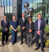 A photo of Ali Yousuf, Dr Lip Lee, Brian Deaver, Dr Aisha Umar and Jonathan Martin standing in front of the sculpture outside The Christie's main entrance.