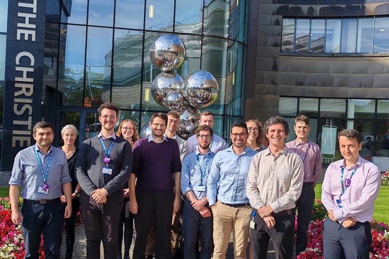 A photo of The Christie Medical Physics and Engineering (CMPE) Magnetic Resonance (MR) Physics group standing outside the Oak Road entrance at The Christie.