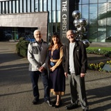 A photo of Christie patients Ian Cameron and Ian Gresty with Christie staff member Charlotte Finchett standing outside The Christie's main entrance.