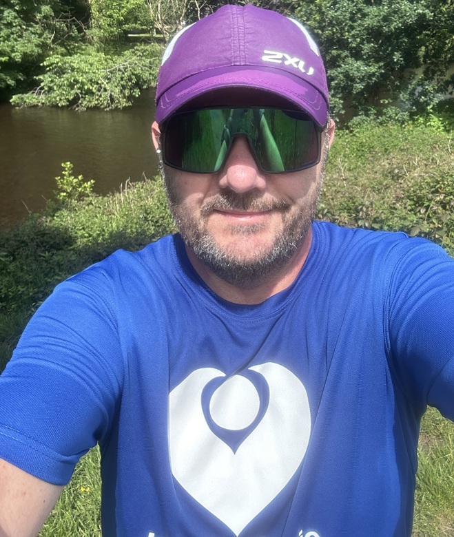 A photo of Christie fundraiser Mark Dutton wearing sunglasses, a cap and a Christie Charity t-shirt.