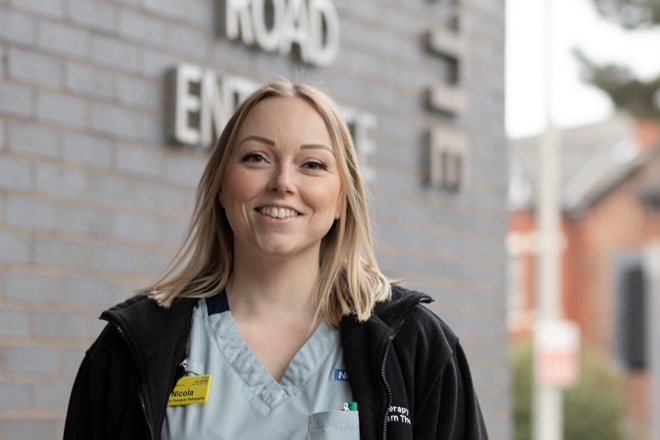 A photo of Nicola Dunwoodie, apprentice therapeutic radiographer at The Christie, standing outside the Palatine Road entrance of The Christie hospital.