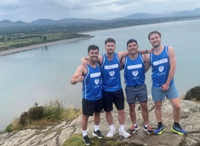 A photo of James Madeira, Joel ‘JJ’ Kinsella, Joe Madeira and Joel Walsh in blue Christie Charity t-shirts standing in front of Loch Ness.