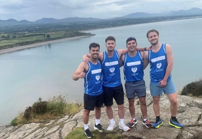 A photo of James Madeira, Joel ‘JJ’ Kinsella, Joe Madeira and Joel Walsh in blue Christie Charity t-shirts standing in front of Loch Ness.