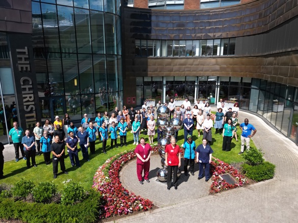A photo of a large group of staff members standing outside the front of The Christie.
