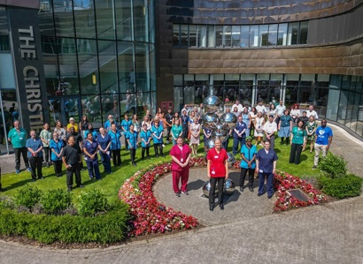 A photo of a large group of staff members standing outside the front of The Christie.