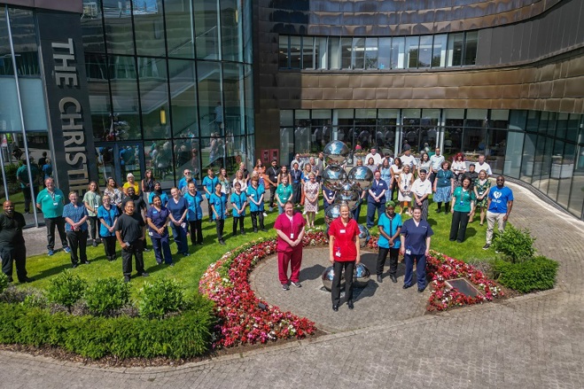 A photo of a large group of staff members standing outside the front of The Christie.