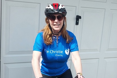 A photo of Christie patient and fundraiser Jeanette Joyce sitting on a bike wearing a Christie cycling jersey and sunglasses.