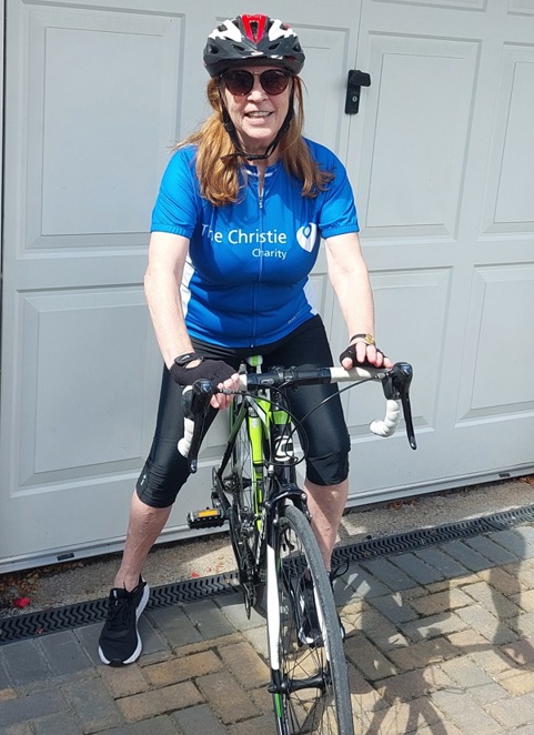 A photo of Christie patient and fundraiser Jeanette Joyce sitting on a bike wearing a Christie cycling jersey and sunglasses.