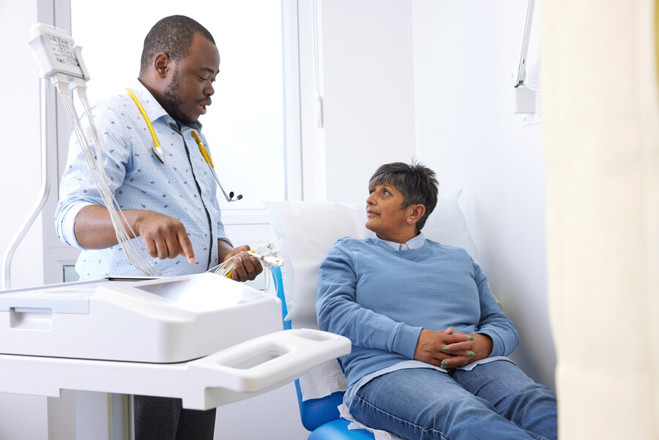 A photo of a male staff member treating a female patient, who is sitting in a chair.