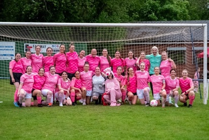 A photo of Meghan Glynn and the Worsley Wanderers FC women's football team wearing their pink football kit and standing in front of a goal.
